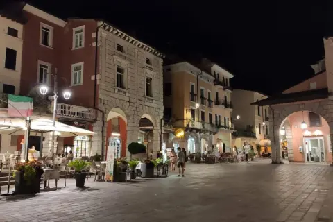 Serata nel centro storico Desenzano del Garda, con locali illuminati e tavolini all'aperto.