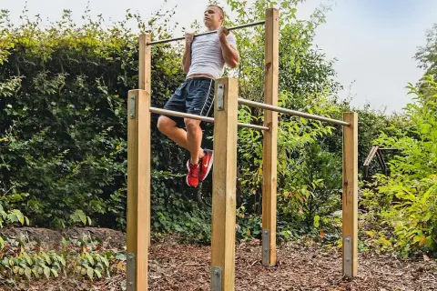 Man tränar pull-ups på ett utegym. Enkla och robusta konstruktioner som inspirerar till att bygga utegym.
