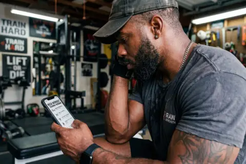 Man with red beard wearing a neck harness in a home gym.