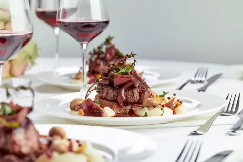 Eleganckie danie z wołowiny z puree i grzybami, podane z czerwonym winem. Zastanawiasz się, ile za talerzyk na wesele?