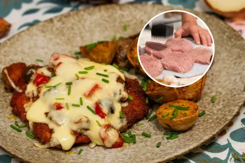 Pyszny kotlet po zbójnicku, zapieczony z serem i warzywami, podany z pieczonymi ziemniakami. W rogu widać surowe mięso do kotleta.