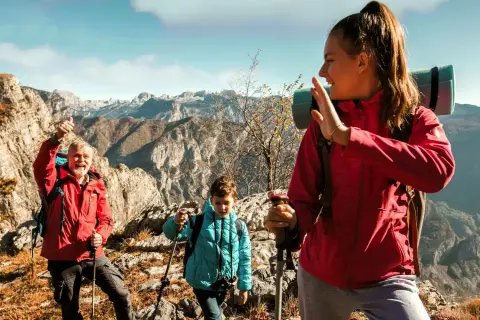 Familia disfrutando de la vista en la montaña, con ropa adecuada para la montaña y equipo de senderismo.