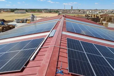 Paneles solares cubren el tejado rojo de un edificio industrial, capturando la energía del sol.