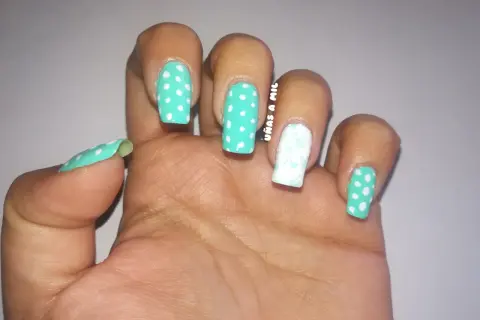 Uñas sevillanas con diseño de lunares turquesa y blanco, y un dedo decorado con un delicado estampado floral.