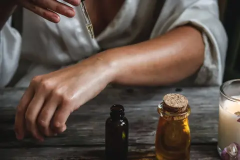 Una persona aplica aceite esencial en su brazo, mostrando cómo usar aceites esenciales para el cuidado de la piel.