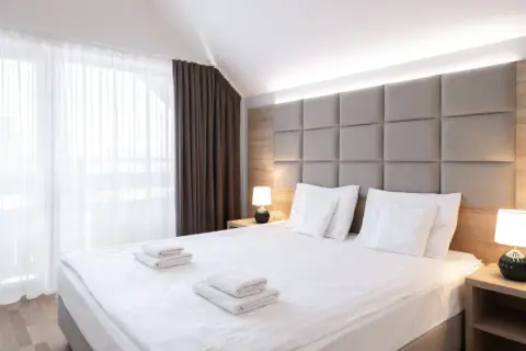 Przytulna sypialnia z dużym łóżkiem, miękkim zagłówkiem i zasłonami. "Room only" to oferta noclegu bez wyżywienia.