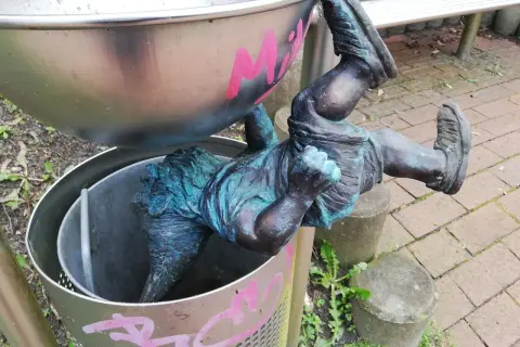 Ein bronzener Zwerg hängt kopfüber in einem Mülleimer in Hitzacker. Die Zwerge sind ein beliebtes Motiv.
