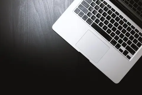 Laptop na czarnym blacie. Dowiedz się, jak otworzyć plik rar, korzystając z klawiatury i touchpada.
