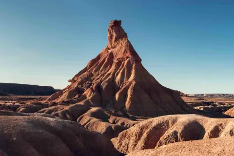 Paisaje desértico en Navarra, ideal para una aventura en camper. Formaciones rocosas erosionadas bajo un cielo azul.