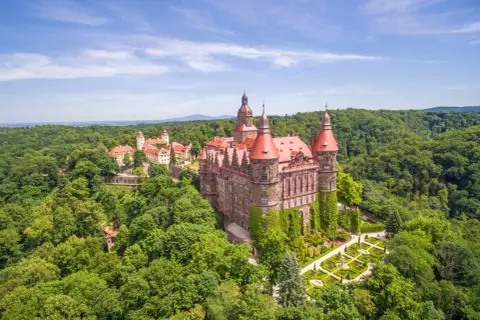 Majestätisches Schloss Kynast, eingebettet in grüne Wälder in Niederschlesien, mit roten Dächern und gepflegten Gärten.