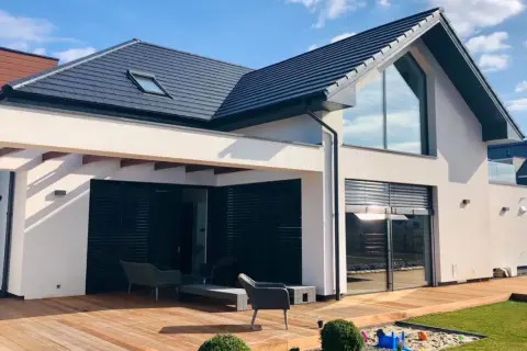 Nowoczesny dom z tarasem i dużymi oknami. Projekt domu 60m2 z drewnianym tarasem i piaskownicą dla dzieci.
