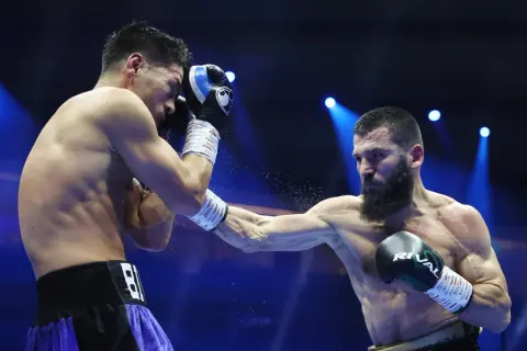 A light heavyweight boxer attempts to block a powerful punch from a heavyweight opponent in a dramatic boxing match.