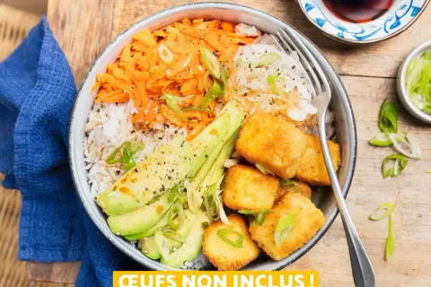 Bol coloré avec riz, carottes râpées, avocat et cubes de tofu teriyaki croustillants, garni de ciboule.
