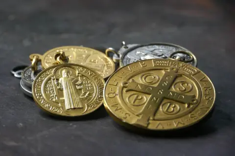 Kilka złotych i srebrnych medalików, w tym cudowny medalik z wizerunkiem świętego.