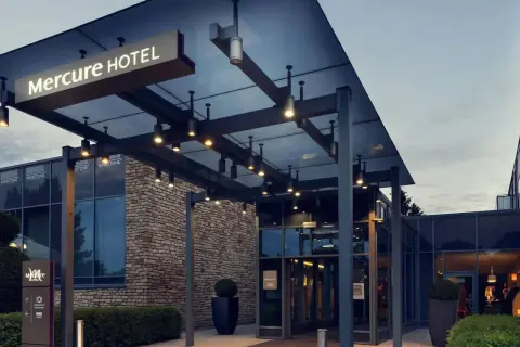 Nowoczesne wejście do hotelu Mercure w Gdańsku, z kamienną fasadą i oświetlonym zadaszeniem.