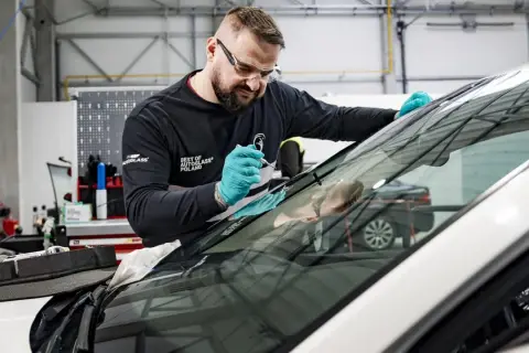 Fachowiec z Autoglass naprawia pęknięcie na szybie. Sprawdź autoglass cennik usług.