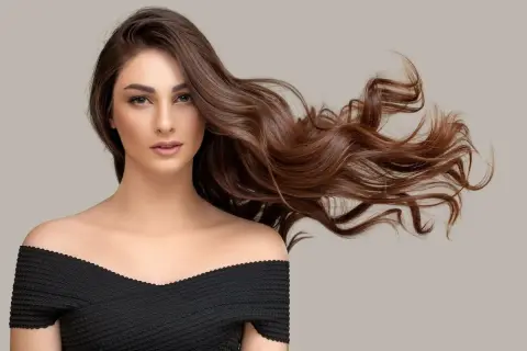 Mujer con cabello castaño ondulado y largo, con un vestido negro. ¿Buscas como quitar el tinte del pelo?