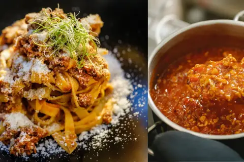 En tallrik med krämig pasta bolognese toppad med riven ost och en kastrull med den rika köttfärssåsen.