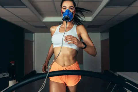 Kobieta w masce biegowa na bieżni, mierząca VO2 max.