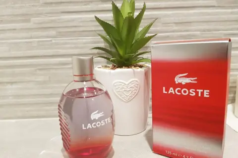 Perfumy męskie Lacoste Red 125ml w szklanej butelce obok czerwonego kartonika.