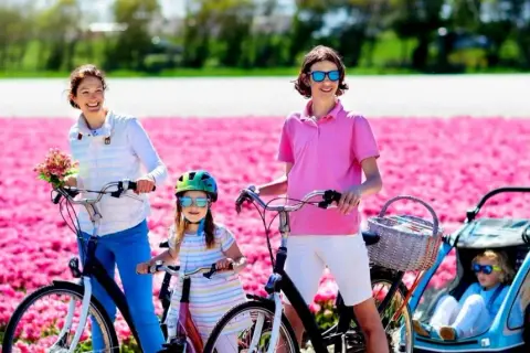 Familia disfrutando de un paseo en bici por campos de tulipanes rosas en Holanda.