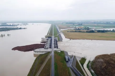Ogromna tama i budowle hydrotechniczne walczą z żywiołem. Woda sięga pól uprawnych, a w oddali widać zalane tereny. To obraz powodzi błyskawicznej.