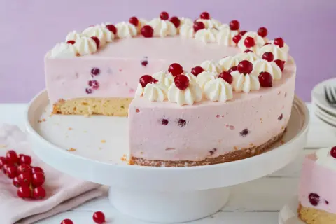 Eine köstliche Johannisbeertorte mit Joghurt, verziert mit Sahnetuffs und frischen roten Johannisbeeren.