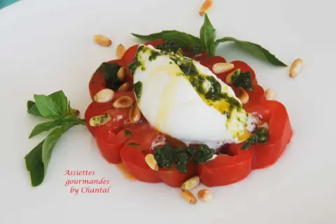 Tomate burrata gastronomique, un délice estival avec pesto, pignons et basilic frais.