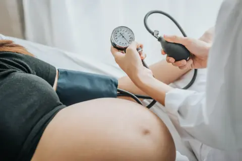 Lekarz mierzy ciśnienie w ciąży u ciężarnej kobiety. Monitoruje jej zdrowie.