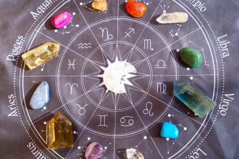 Kamienie szlachetne, w tym lapis lazuli, ułożone wokół znaku zodiaku na czarnym tle.
