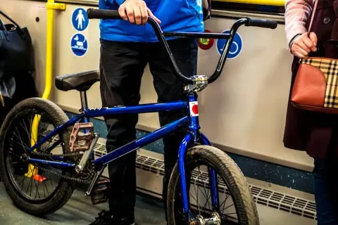 Chłopak z niebieskim rowerem BMX w autobusie, gotowy do podróży.