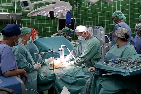 Zespół chirurgów w zielonych fartuchach i maseczkach podczas operacji.