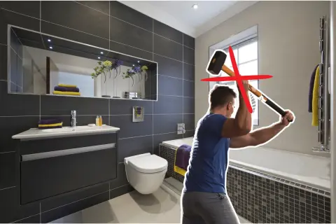 Un homme s'apprête à démolir une salle de bain moderne avec une masse. Une croix rouge indique que cette méthode n'est pas recommandée pour la renovation carrelage.