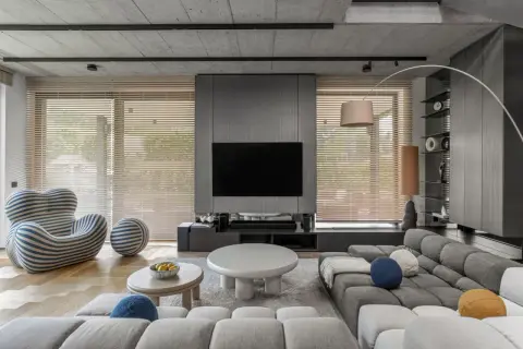Nowoczesne, minimalistyczne wnętrza z szarą sofą, designerskim fotelem i betonowym sufitem.