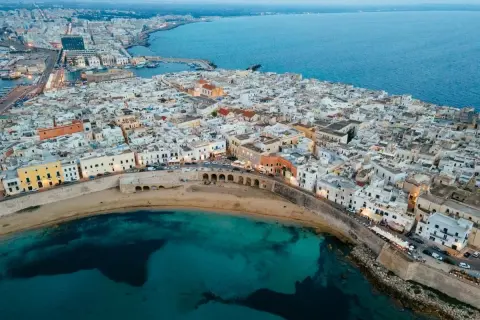 Gallipoli vecchia: un labirinto di vicoli bianchi che si affacciano sul mare turchese, con un'antica muraglia che abbraccia la costa.