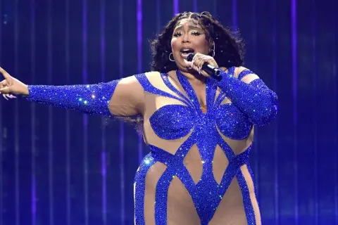 Sängerin in blauem Glitzer-Outfit singt mit Mikrofon, die Arme ausgestreckt. Ein Auftritt, der nach dem besten Lied klingt.