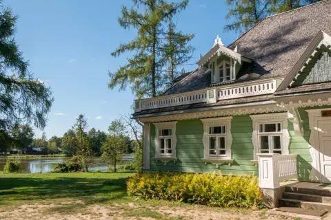 Zielony dworek z białymi zdobieniami, otoczony drzewami i jeziorem. Idealne miejsce na spokojny spacer i zapoznanie się z historią - białowieża plan zwiedzania.