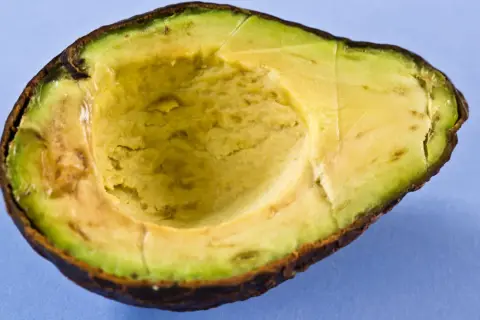 Halbierte Avocado auf blauem Hintergrund. Die Avocado-Wirkung auf die Haut ist bekannt, sie ist reich an Vitaminen und gesunden Fetten.