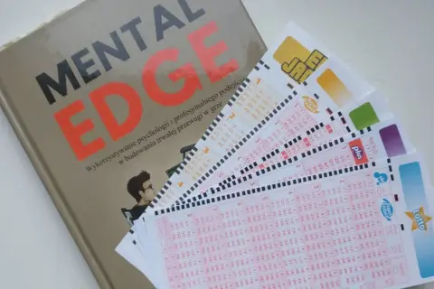 Książka "Mental Edge" i kilka kuponów Lotto ułożonych na białym tle.
