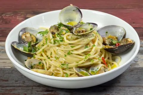 Spaghetti alle vongole, un piatto gustoso con vongole fresche e prezzemolo, pronto per essere gustato.