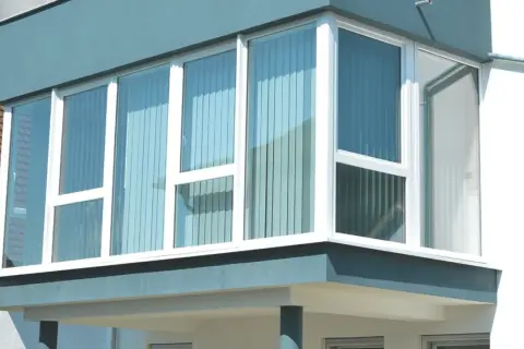 Moderner Anbau mit großen Fenstern, der einen Balkon zum Wintergarten umbauen lässt.