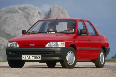 Czerwony Ford Orion z parą uśmiechniętych ludzi w środku, jadący po górskiej drodze.