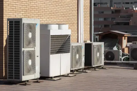 Unidades de aerotermia Repsol en una terraza, junto a un edificio de ladrillo.