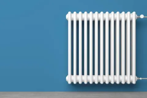 Radiatore bianco su muro blu. Un termotecnico cosa fa? Si assicura che il calore sia distribuito in modo efficiente.