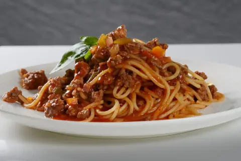 Ein Teller Spaghetti Bolognese, liebevoll zubereitet, mit frischem Basilikum garniert. Perfekt, um bolognese selber machen zu lernen.