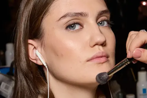 Applicazione di un pennello per il trucco sul viso, forse per schiarire il fondotinta o sfumare il blush.