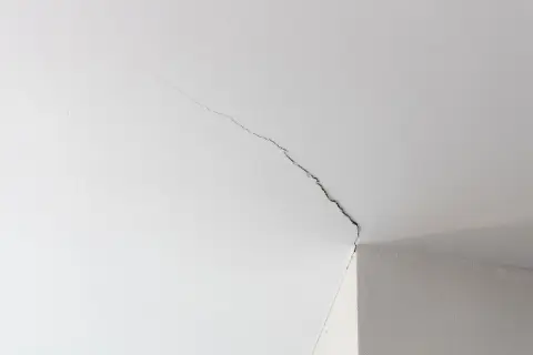 Fissure sur un plafond blanc, signe d'une trame de renovation nécessaire.