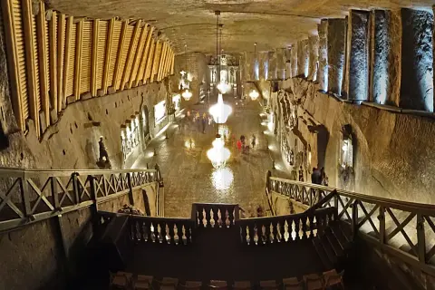 Wielka komora kopalni soli „Wieliczka” z kryształowymi żyrandolami i turystami. Opinie o tym miejscu są zachwycające.