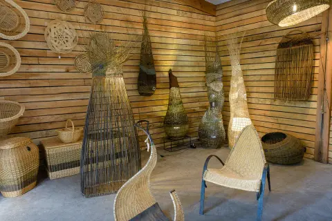 Atelier de vannerie. Des paniers, des luminaires et des sièges en osier, prêts à peindre de l'osier, décorent les murs en bois.