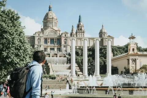 Mężczyzna z plecakiem podziwia fontanny i Pałac Narodowy w Barcelonie. Piękna, słoneczna barcelona pogoda listopad.